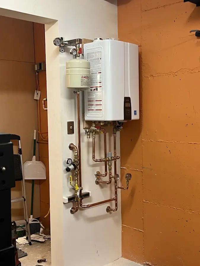Plumbing technician inspecting water heater connections in Lee